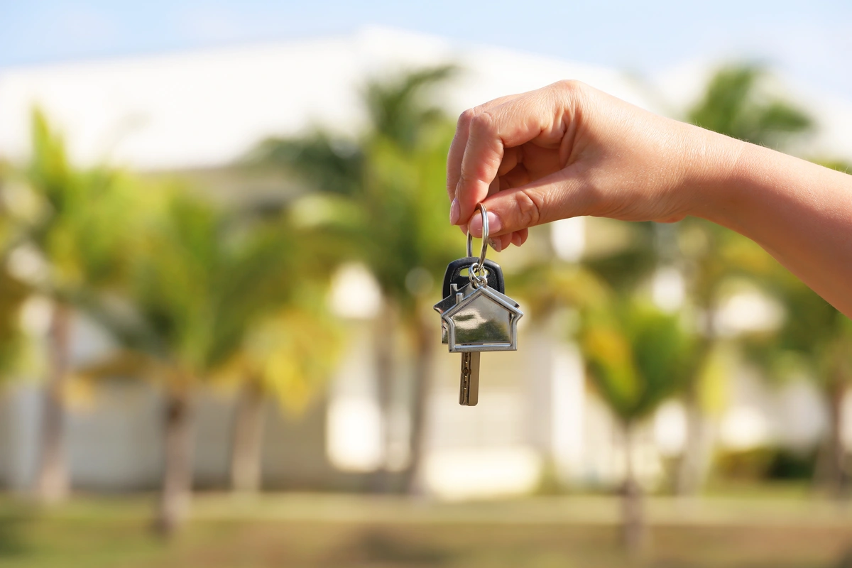 keys held by real estate agent in front of a florida home for sale in need of a roof inspection