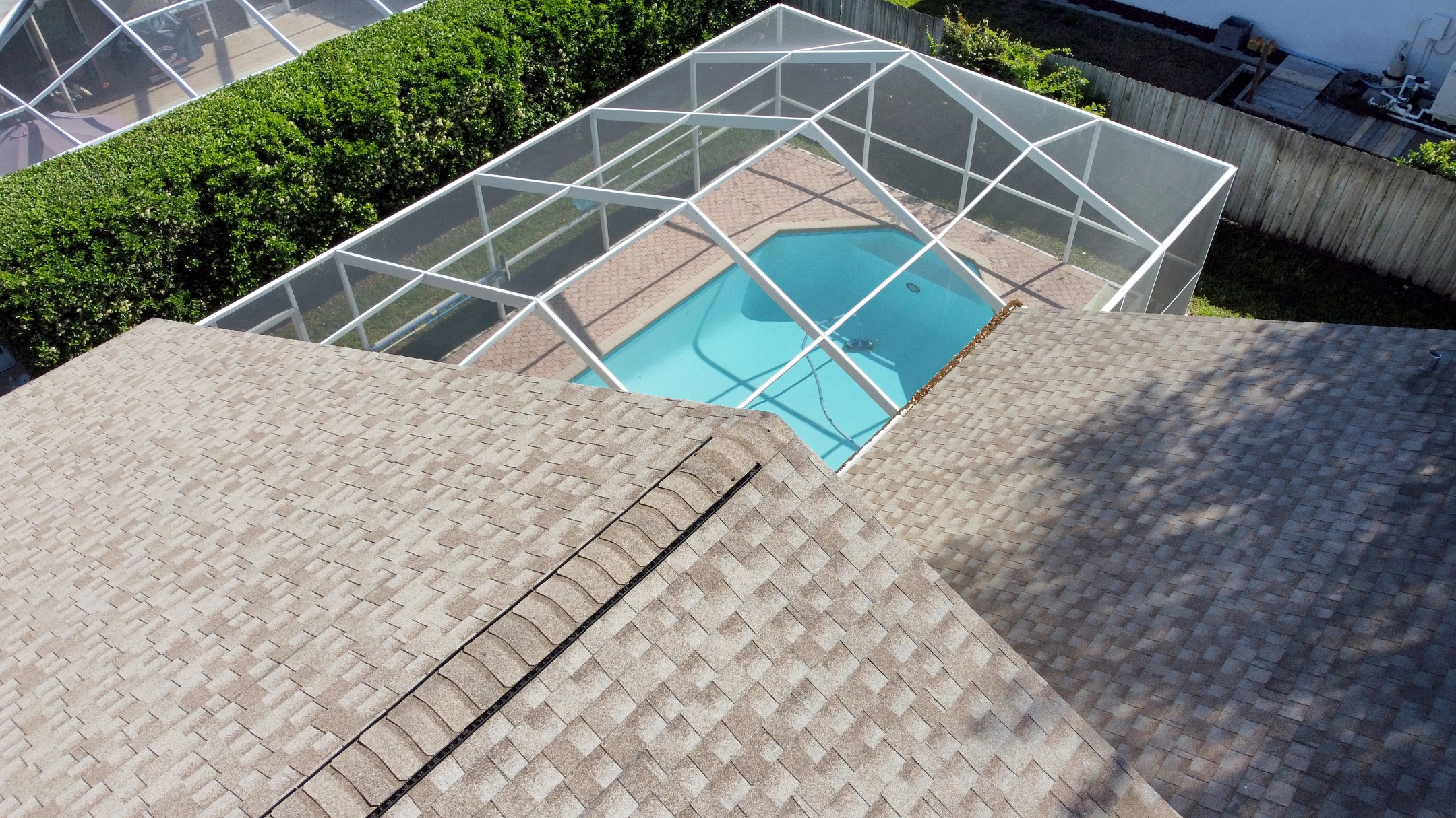 drone aerial view of florida shingle roof with caged in pool