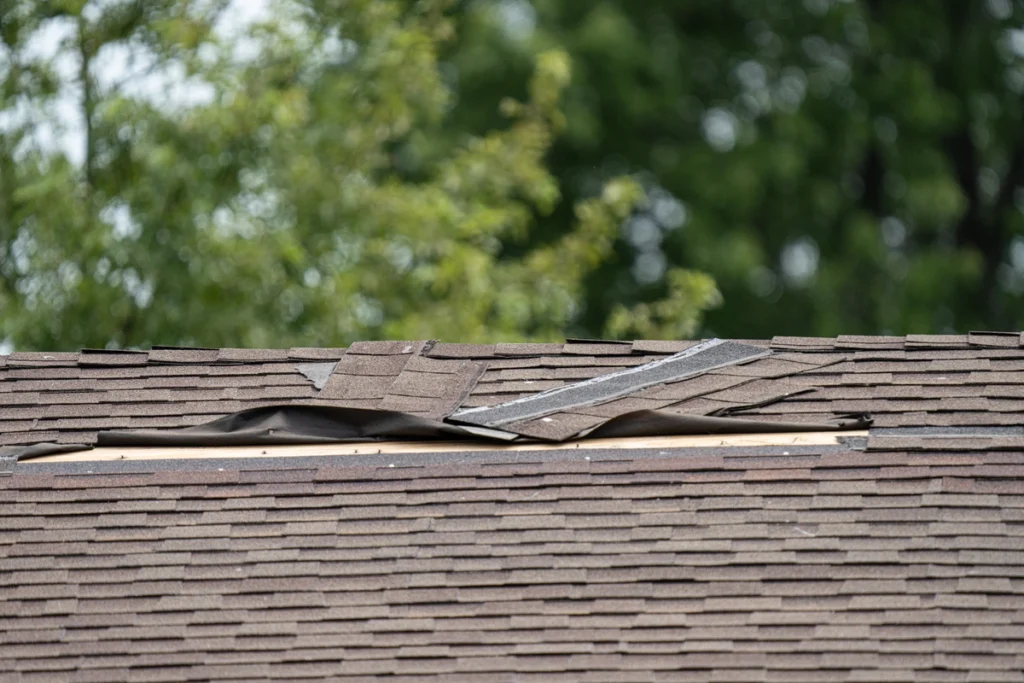 close up of asphalt roof missing shingles after storm damage
