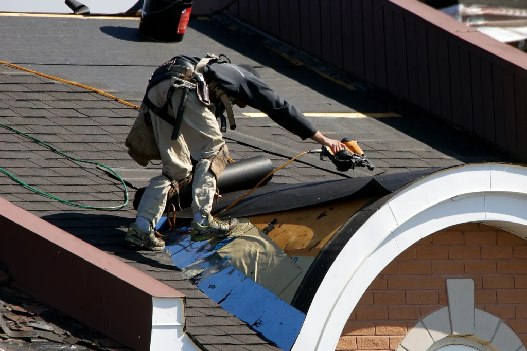 worker repairing roof using nail gun 