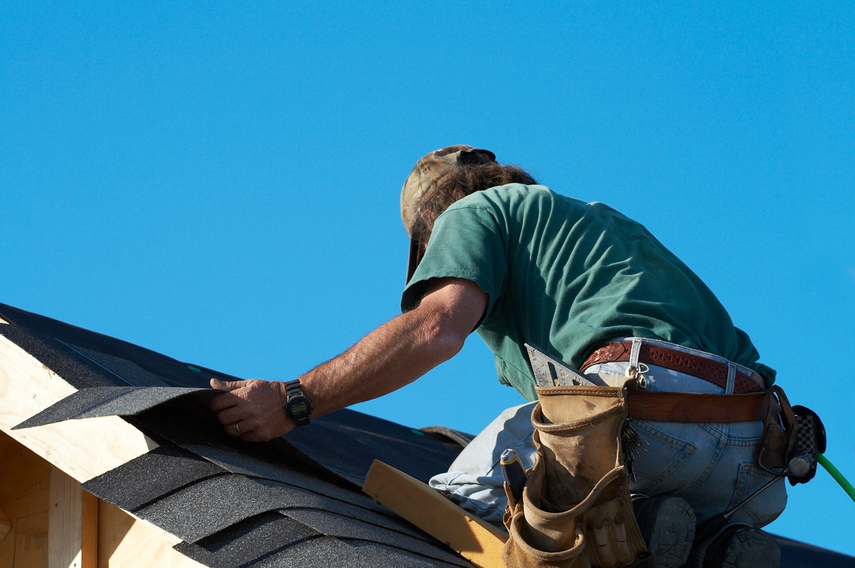 close up of contractor replacing blown off shingles on roof