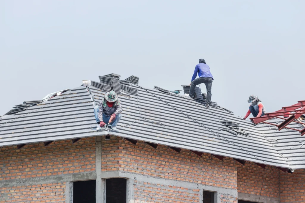construction workers installing a concrete roof on the house