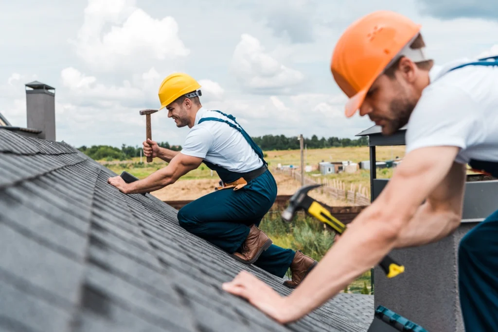 two professional roofers repairing the house roof