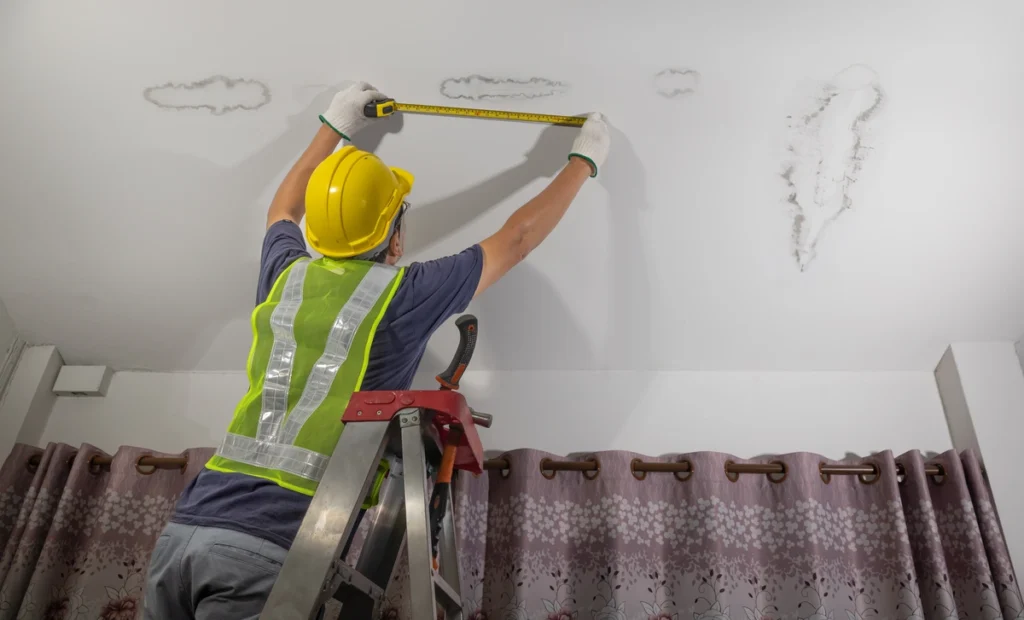 worker measuring ceiling stains