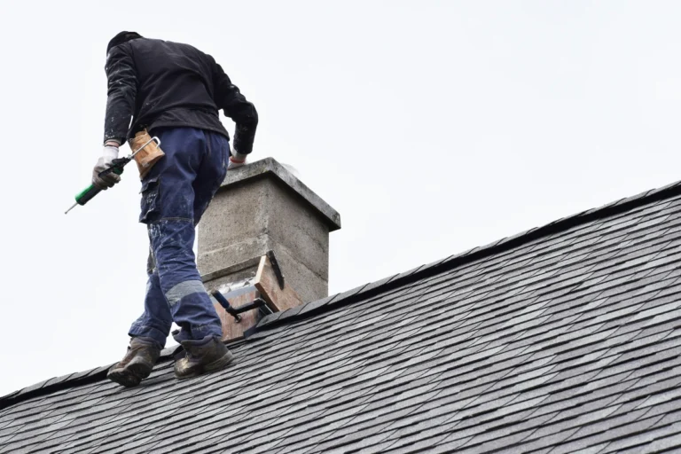 roofer performing chimney flashing repair on a roof